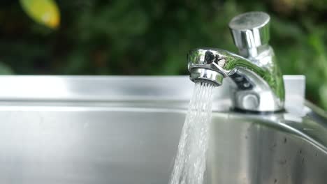 water flowing from a faucet into a stainless steel sink