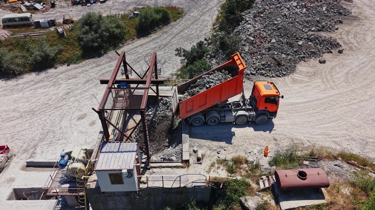 Camion consegna ghiaia in un cantiere edile con tempo soleggiato