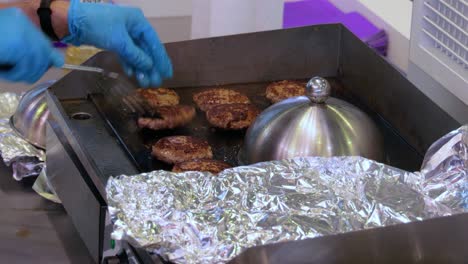 la carne de res se cocina en una sartén caliente. comida callejera, el chef lanza hamburguesas con una espátula.