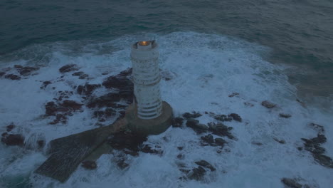 bajo el resplandor de la tarde: el faro de mangiabarche en todo su esplendor con olas salpicando por cerdeña
