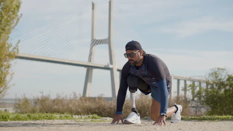 focused sportsman with artificial leg running from crouch start at the park in the morning 1