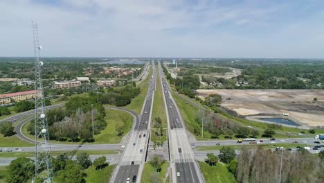 Reverse-Aerial-Dolly-Shot-of-a-Radio-Tower-Next-to-Highway-in-Florida-on-a-Sunny-Day