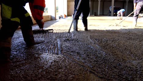 los trabajadores de la construcción están nivelando el hormigón vertido en el suelo