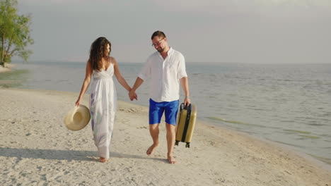 Ein-Liebespaar-Geht-An-Einem-Tropischen-Strand-Entlang-Und-Trägt-Eine-Reisetasche-Steadicam-Aufnahme