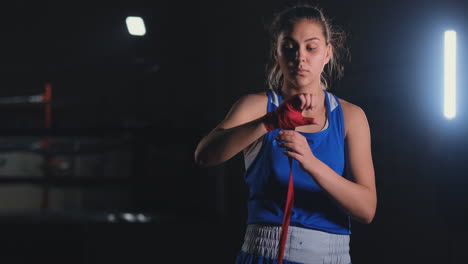 mujer está envolviendo las manos con envolturas de boxeo amarillas. autodefensa para mujeres. aislado en negro con uñas rojas. mano y puño fuertes, listo para la lucha y el ejercicio activo