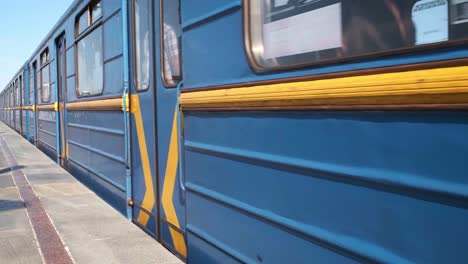 cinemagraph - blue subway train with people inside moving fast, view from metro station. close up for windows of subway train passing fast