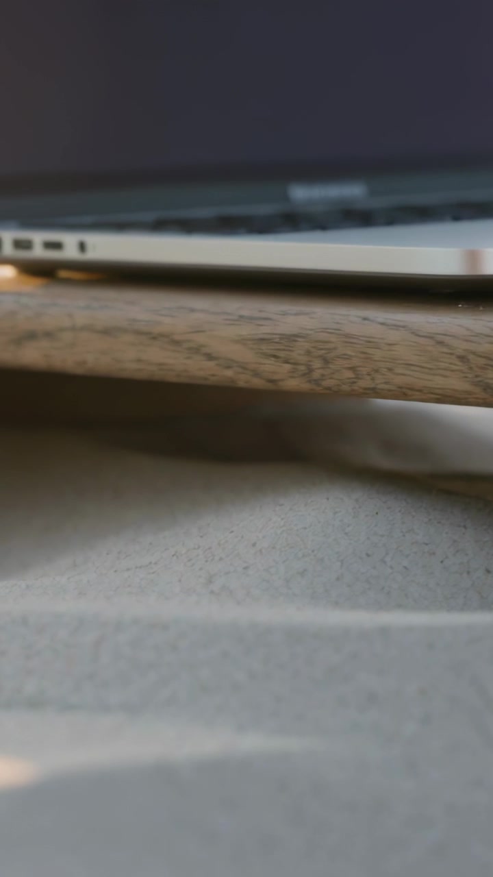 Vertical video: Panning camera up-right, showing closed silver laptop on plank over sheet for hinge