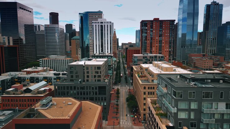 Denver, USA, 28 luglio 2025: si staglia sopra la lunga e vuota strada rettilinea che attraversa il moderno paesaggio urbano. Denso cielo nuvoloso sopra Denver, Colorado, USA