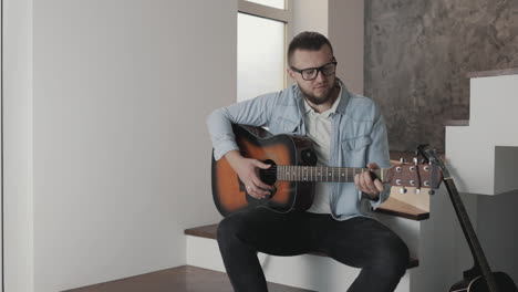 músico masculino ajustando y tocando la guitarra en casa