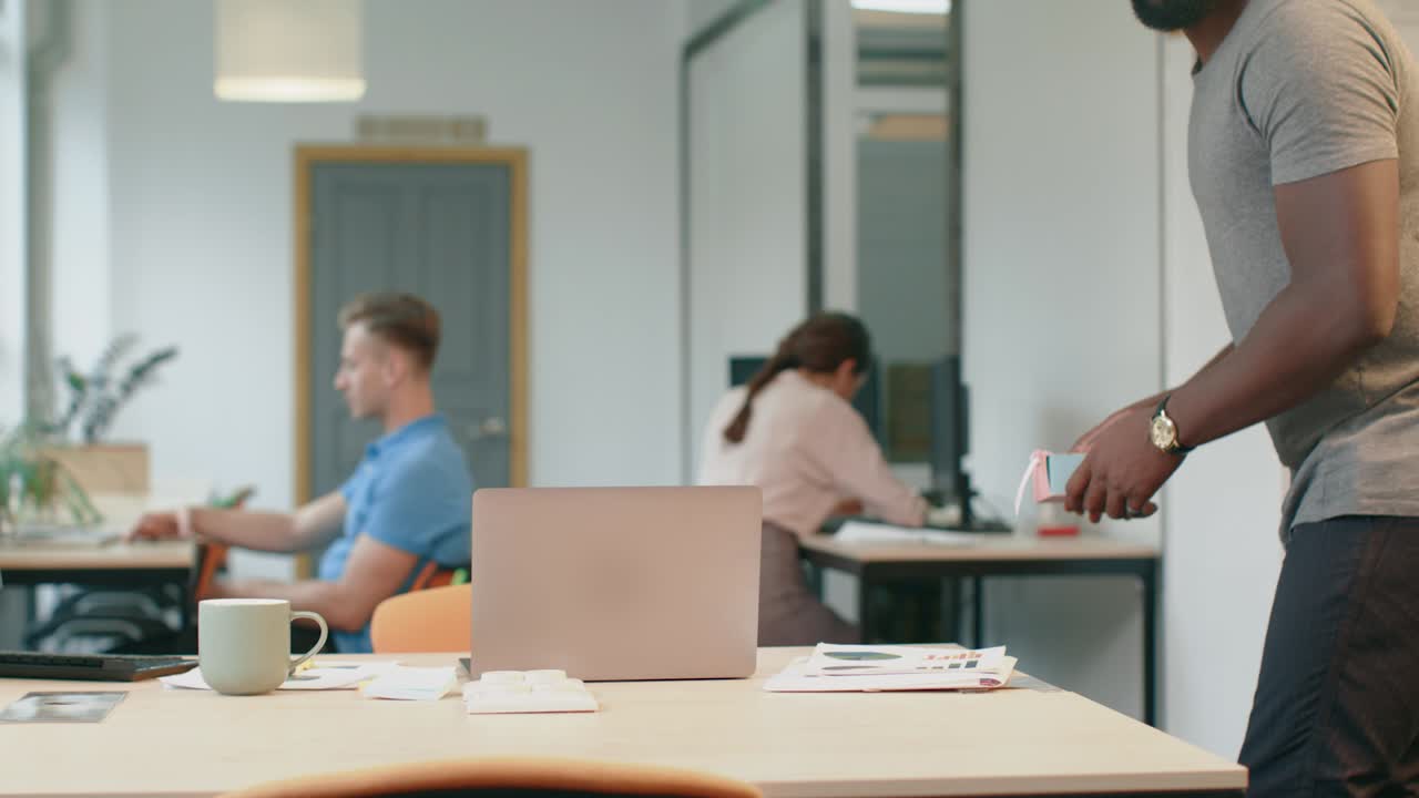 African man putting gift at coworking space. Romantic man leaving small present
