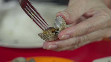 Nahaufnahme-Erschossen-Hände-Mit-Gabel-Herausnehmen-Blutmuschel-Form-Shel-Meeresfrüchte-Indonesischen-Gericht