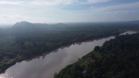 Aerial-drone-view-of-a-long,-brown-winding-river-through-tropical-rainforest