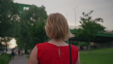 follow shot of attractive blonde woman in red dress