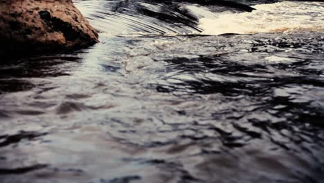 a steep dark river with a rock