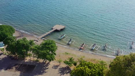 aerial-overhead-of-jukung-boats-anchored-on-coastline-of-Lovina-Beach-with-sun-reflecting-on-sunny-day-in-Bali-Indonesia