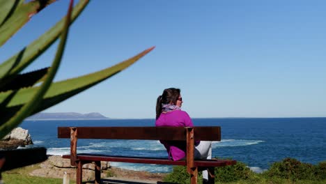 Mujer-Pensativa-Sentada-En-Un-Banco-Mirando-Al-Océano