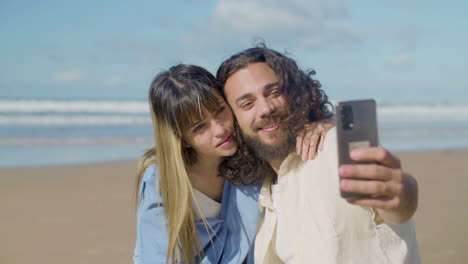 una hermosa pareja tomando una selfie en la orilla del mar.