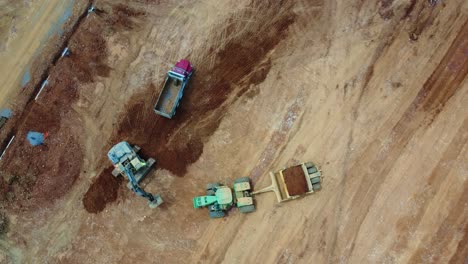 overhead shot of excavator, scraper, and dump truck at construction site