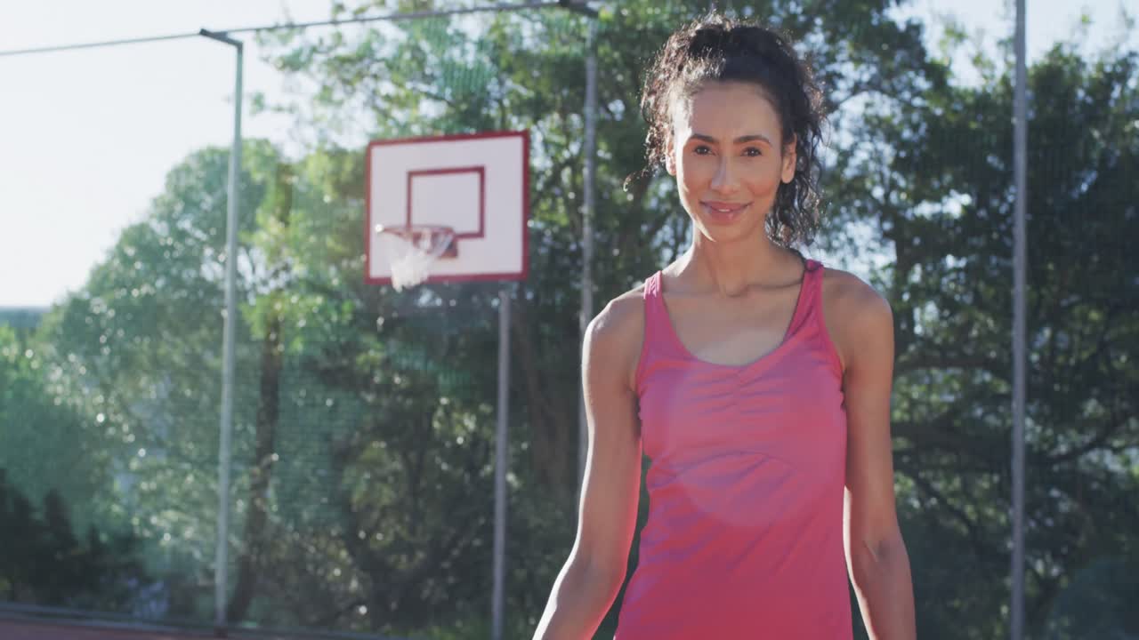 feliz jugadora de baloncesto biracial con la pelota en una cancha soleada, espacio de copia, cámara lenta