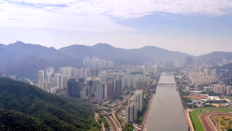 high skyscrapers between the mountains of lion rock country park and shing mun river on a cloudy sunny day