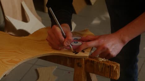 a young man draws a figure on a wooden board for fretwork