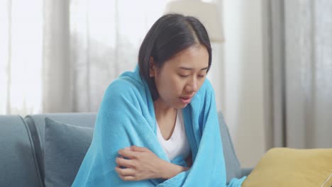 woman wrapped in a blanket, coughing