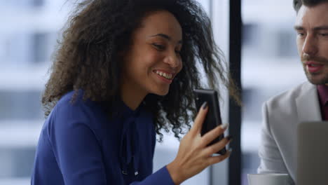 una mujer de negocios afroamericana emocionada mostrando un teléfono móvil