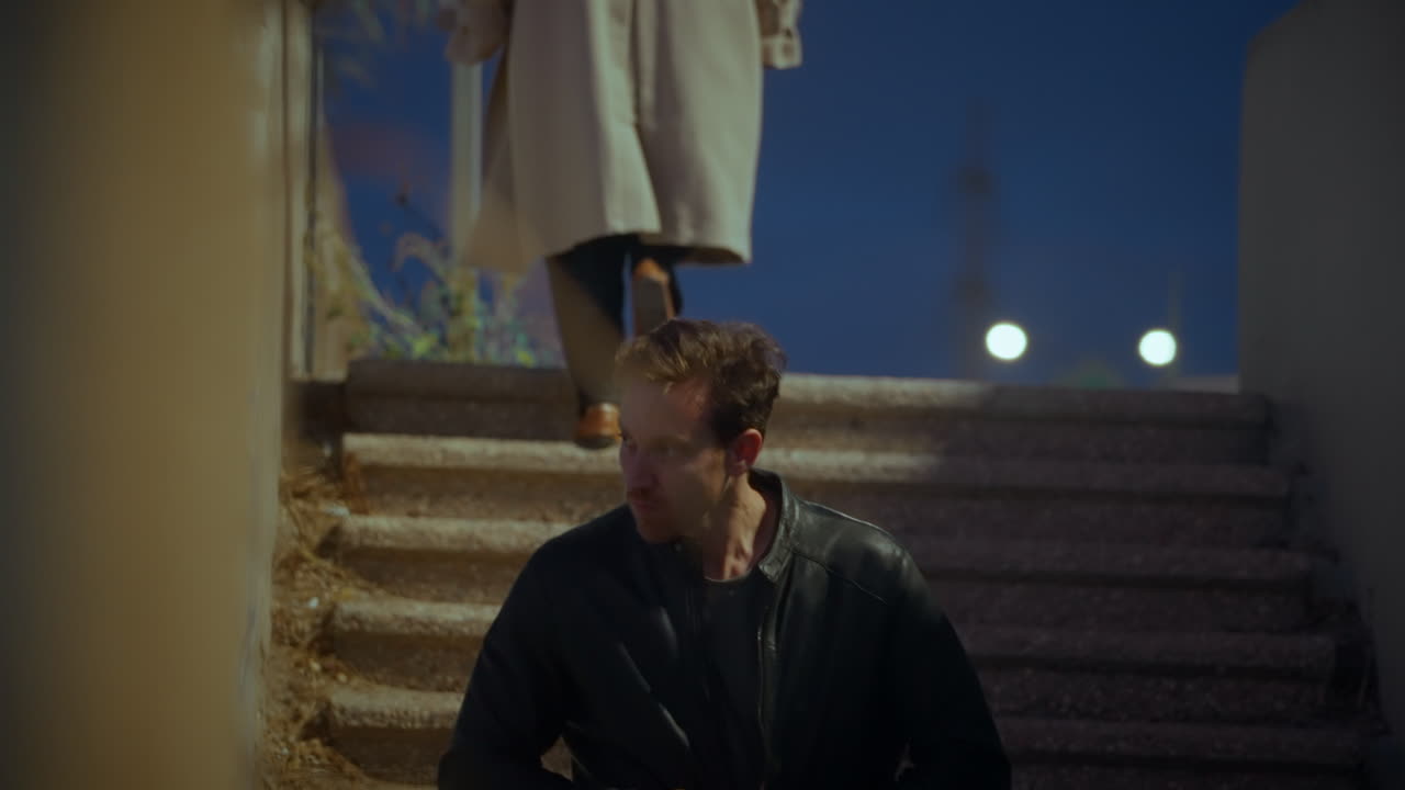 Female agent or spy hands man with leather jacket an envelope with cash or bribe. Government conspiracy business corruption. Secret meetup transaction in street alley at night. Suspicious dirty deal