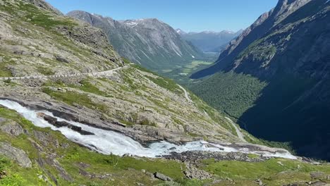 Una-Vista-Impresionante-De-Un-Exuberante-Valle-Verde,-Rodeado-De-Picos-Nevados,-Con-Un-Río-De-Montaña-De-Rápido-Caudal-En-Primer-Plano-Cerca-De-Åndalsnes-Y-El-Innfjorden.