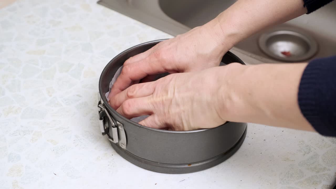 여자 손은 금속 형태의 요리 종이를 넣고 달한 디저트 케이크를 기 위해 준비합니다.