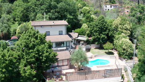 jib down of small mediterranean villa with pool surrounded by trees