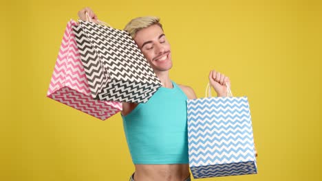 Man holding shopping bags on yellow background