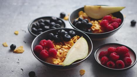 golden cornflakes with fresh fruits of raspberries, blueberries and pear in ceramic bowl