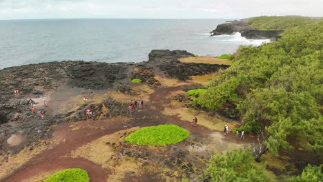 Draufsicht-Auf-Menschen,-Die-Zum-Pont-Naturel-Auf-Einer-Mit-Vulkangestein-Bedeckten-Klippe-In-Mauritius-Gehen