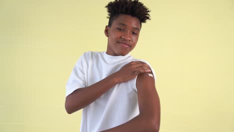 african american teenager showing covid-19 vaccine bandage merrily