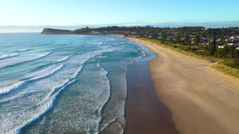 wide cinematic drone shot of lennox head beach and coastline, into the sun