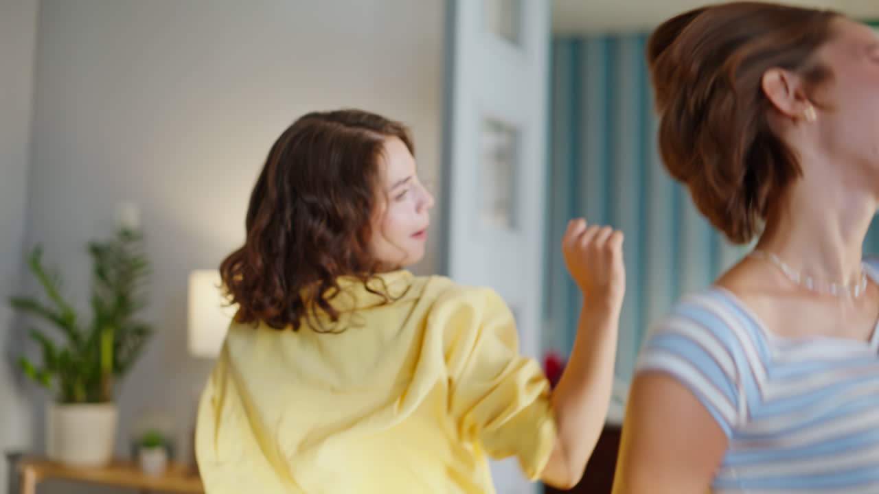 Two women dancing home closeup. Cheerful two brunettes moving bodies singing