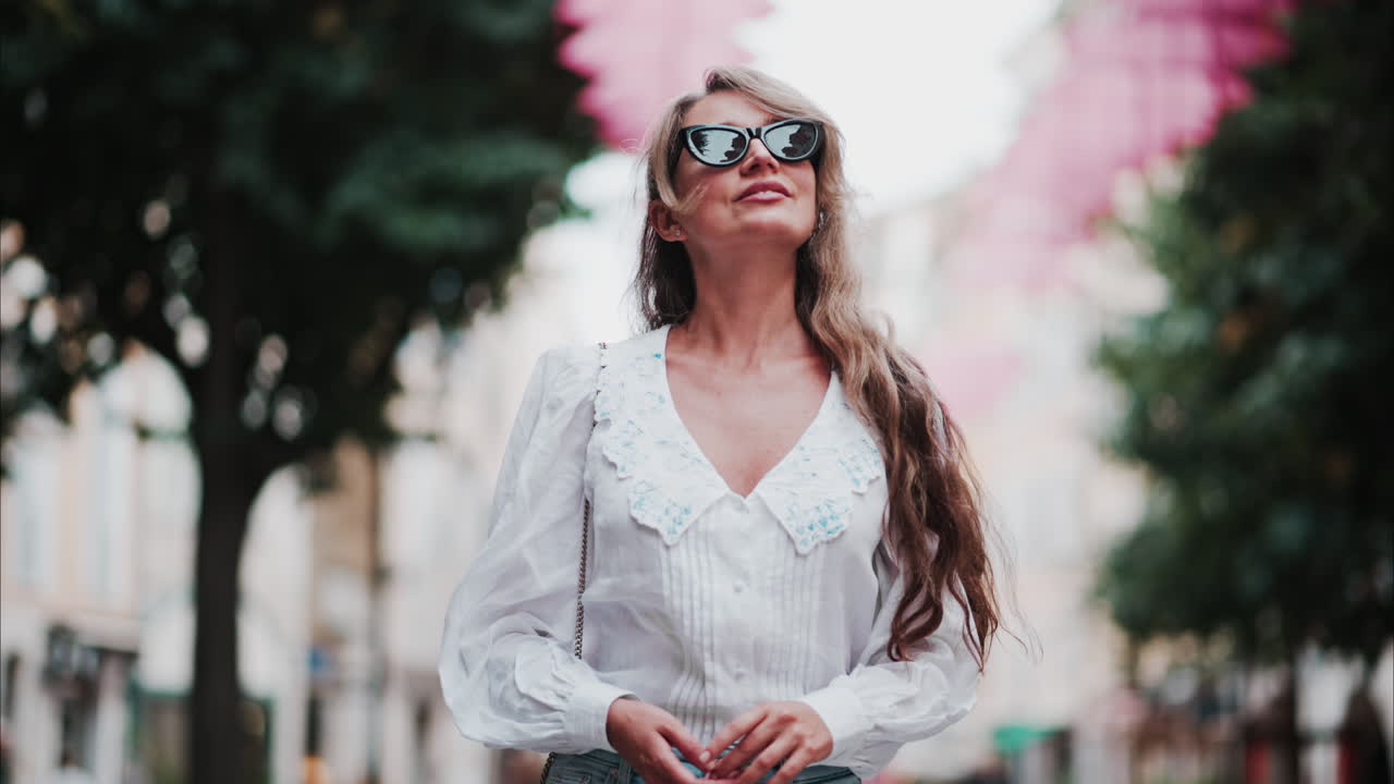 Woman walking under rows of pink umbrellas above the streets of the old town of Grasse, France