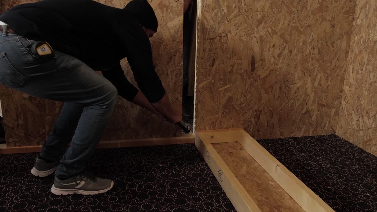 Worker using a caulking gun to seal a wooden wall panel during construction