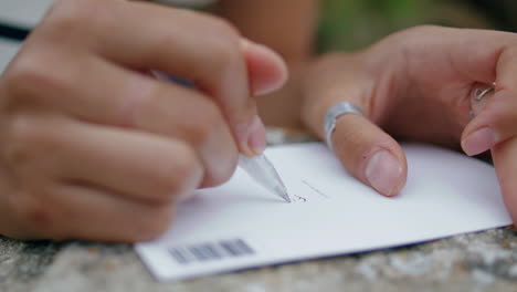 hand writing travel postcard on rock closeup. young student sending greetings