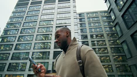 man drinking coffee and using phone in city