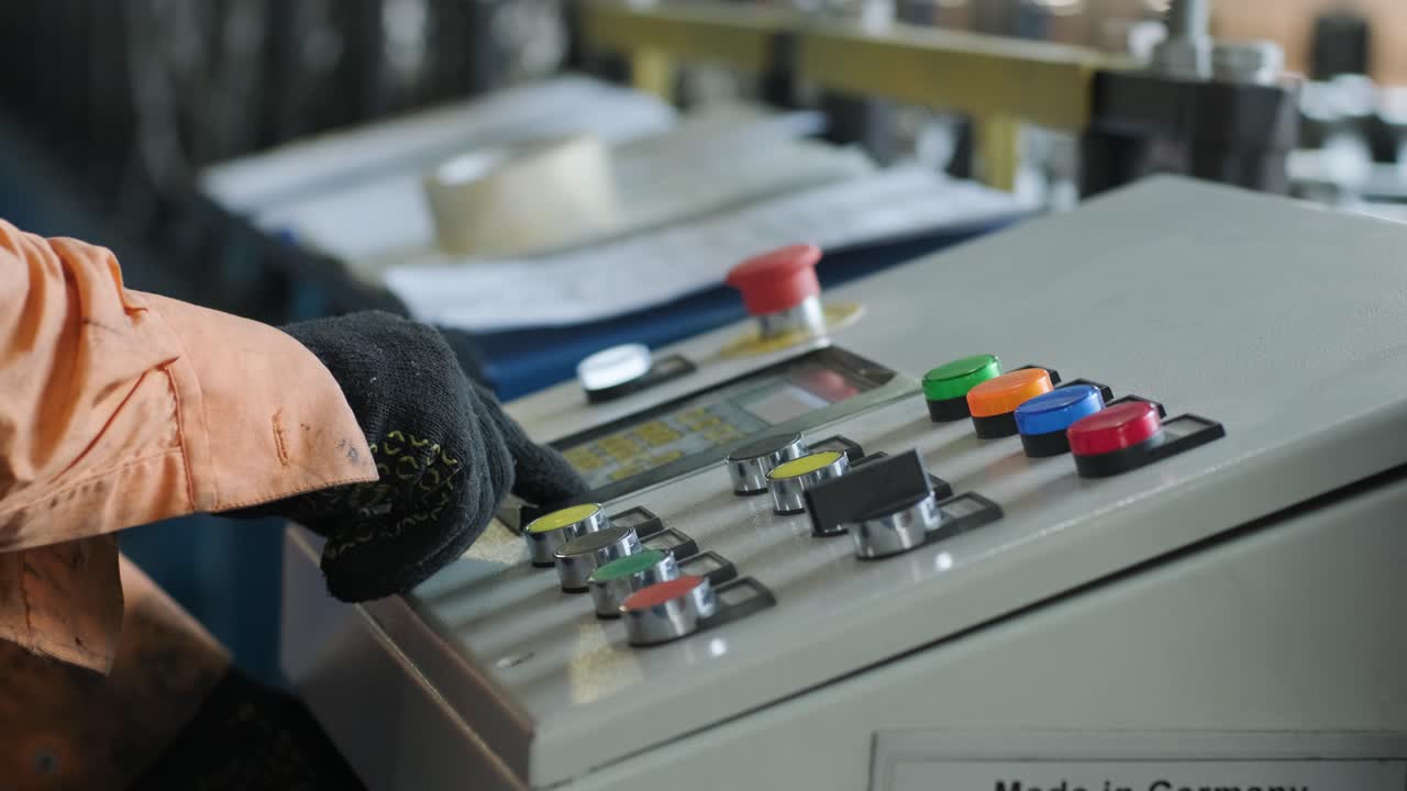 el hombre que trabaja en el panel de control trabaja con una máquina industrial en el primer plano de la fábrica.
