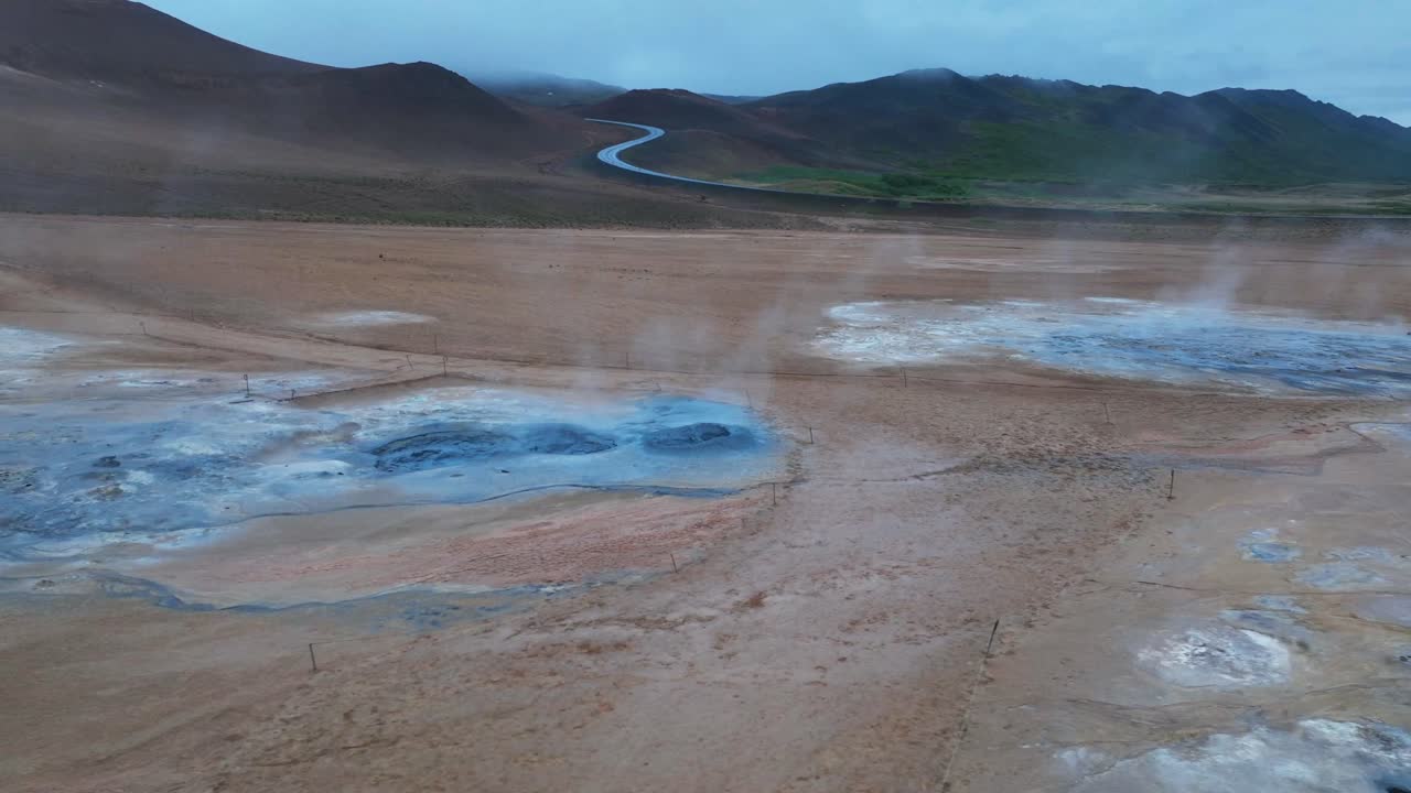Aerial view of hverir geothermal area with boiling hot spring fields at dark cloudy day. Road in mountains in distance. Iceland, Europe