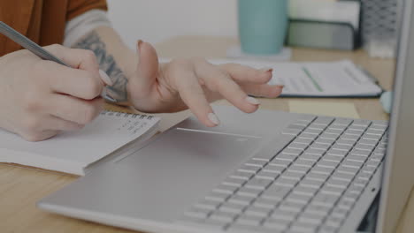woman working on laptop and taking notes