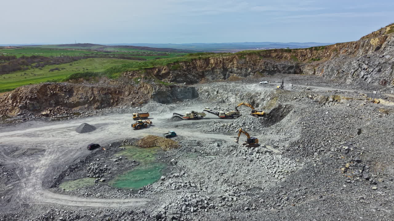 Granite quarry site showing machinery and rock piles during daytime work in an open area