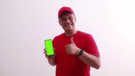 Wow-Sorprendido-Joven-Repartidor-Asiático-Señalando-La-Pantalla-Verde-Del-Teléfono-Celular