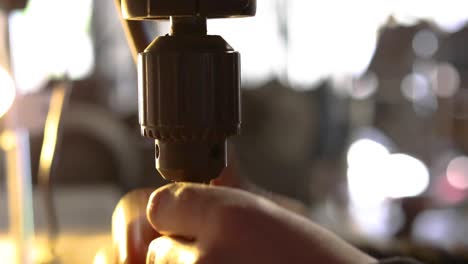 close-up of man's hand's putting drill bit into drill press and then tightening by and then with a chuck key