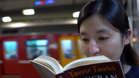 woman reading a book on a subway platform