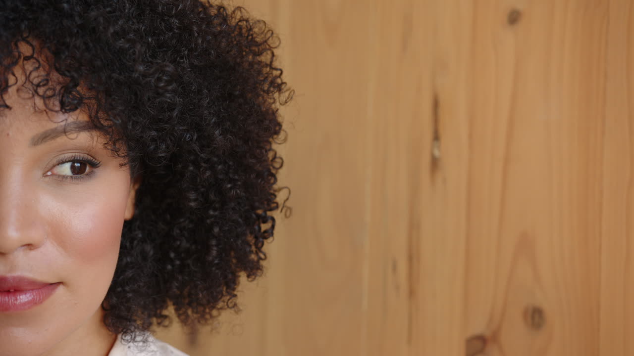 Close-up of woman with curly hair looking to side, focusing on something, copy space