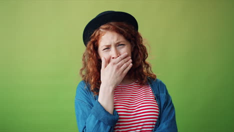 woman with red hair and a hat looking bored
